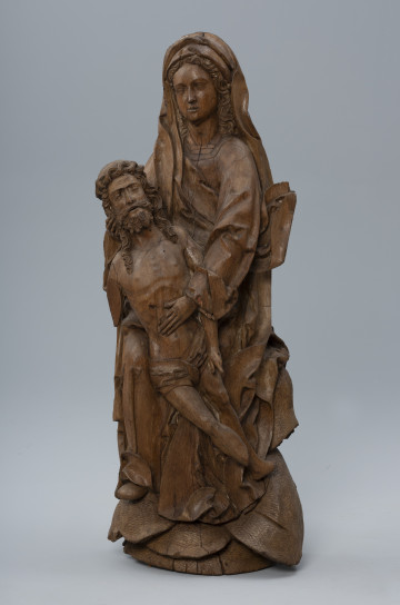 MNS/Szt/222 pieta - ujęcie z przodu; Rzeźba o pionowej kompozycji przedstawia dwufigurową grupę: Marię trzymającą martwe ciało Chrystusa. Sylwetka Marii ukazana frontalnie wsparta jest na kamiennym zboczu porośniętym darnią widocznym po bokach i poniżej postaci. Twarz o zaokrąglonych policzkach otacza falująca fryzura długich włosów. Głowę okrywa długi marszczony welon. Obszerny płaszcz nałożony na suknię o długich szerokich rękawach zagina się tworząc głębokie, światłocieniowe fałdowania i szerokie płaszczyzny na krawędziach. Ciało Chrystusa o nieco pomniejszonych proporcjach oddane jest naturalistycznie. Wsparte na kolanie matki osuwa się diagonalnie od jej prawej dłoni podtrzymującej głowę syna, ku lewej nisko opuszczonej i podpierającej tors tuż poniżej ciętej w szeroko rany w boku. Dłońmi oraz wysuniętym do przodu i ustawionym nieco wyżej swym prawym kolanem podtrzymuje osuwające się diagonalnie martwe ciało Chrystusa o pomniejszonych proporcjach.