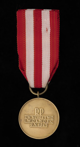 Medal Zwycięstwa i Wolności - Rewers: centralnie czterowierszowy napis (majuskułą): RP / ZWYCIĘSTWO / i WOLNOŚĆ / 9.V.1945. Wiersze napisu podkreślone poziomymi kreskami. Krawędź obustronnie płasko podniesiona. Zawieszenie z przylutowanego uszka i przewleczonego, zlutowanego kółeczka z gładkiego drutu. Wstążka z czerwonego rypsu.