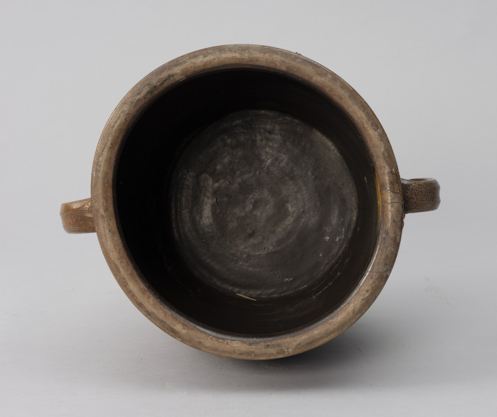 naczynie zasobowe z odrutowaniem - Ujęcie z góry; Duże naczynie zasobowe w kształcie dużego garnka. Dwa taśmowe wzdłużne ucha umiejscowione wysoko. Wewnątrz naczynie powleczone ciemnobrązową emalią.