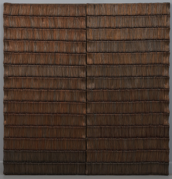 Wrota (Drzwi) - ujęcie z przodu; Kompozycja prostokątna o zbliżonych do kwadratu proporcjach złożona z dwóch symetrycznych drewnianych płyt z przyklejonymi na awersie drucikami ze stali miedziowanej. Na każdej z dwóch płyt druciki zakomponowane w kilkunastu poziomych pasach. Pojedyncze pasy wypełnione ciasno wielokrotnie giętym drucikiem w rytmicznym pionowym układzie.