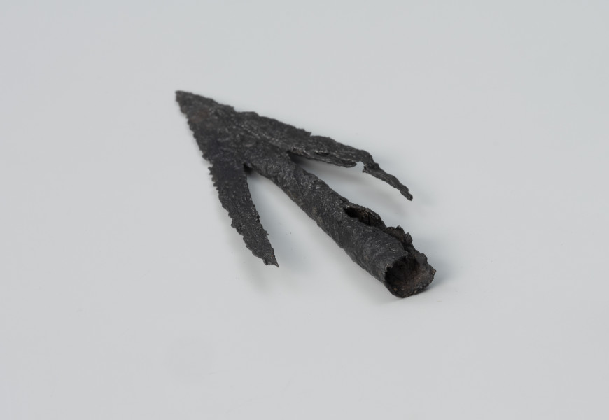 Grot strzały łuku - ujęcie z tyłu; Żelazny grot strzały łuku charakteryzuje się długimi zadziorami liścia i stożkowatą tulejką do osadzenia na drzewcu.