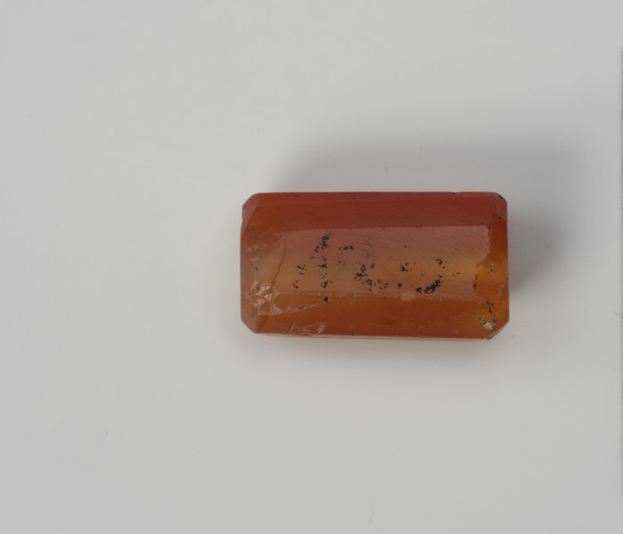 Paciorek wielościenny - ujęcie z drugiego boku; Paciorek z karneolu w kształcie wydłużonego prostopadłościanu, w przekroju ośmioboczny.