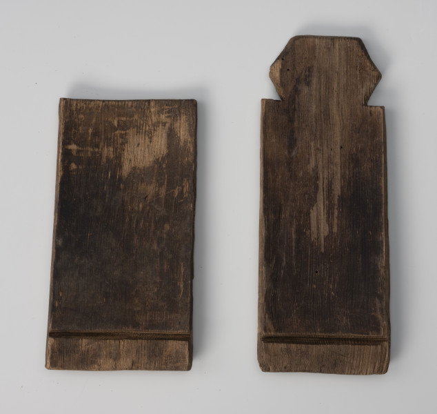 Klepka cebrzyka - ujęcie z tyłu; Klepka wystrugana z drewna współtworząca naczynie typu cebrzyk, w kształcie prostokąta, lekko wklęsła od strony wewnętrznej, z wątorem do osadzenia dna i główką do mocowania sznura. Część wewnętrzna lekko nadpalona. Z lekkimi uszkodzeniami powierzchni.