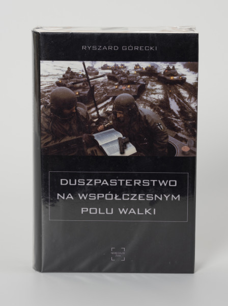 Ryszard Górecki. Duszpasterstwo na współczesnym polu walki - ujęcie z przodu; Obłożony w foliową koszulkę obiekt-książka. Na frontowej stronie czarnej okładki okładce od góry białe napisy: nazwisko autora (RYSZARD GÓRECKI), fotografia z pola bitwy (na pierwszym planie dwaj żołnierze czytający Biblię, w tle kawalkada czołgów sunących przez rozmokłe, częściowo zaśnieżone pole), poniżej zdjęcia: tytuł publikacji (DUSZPASTERSTWO NA WSPÓŁCZESNYM POLU WALKI) i logo wydawnictwa Niewidzialny Znak.