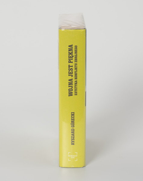 Ryszard Górecki. Wojna jest piękna. Estetyka konfliktu zbrojnego. - ujęcie z boku; Obłożony w foliową koszulkę obiekt-książka. Okładka w kolorze limonkowym. Na grzbiecie okładki od góry: tytuł publikacji, nazwisko autora i logo wydawcy.