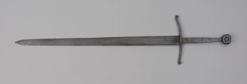 miecz typu XIIIa H2 1b (Oakeshott) - ujęcie z przodu; Miecz w typie: XIIIa, H2, 1b. Głownia o dł. 88,1 cm i szer. 4,9 cm, prosta, jednosieczna ze zbroczem, lekko zbieżna ku sztychowi. Sztych kończysty. Trzpień głowni lekko zwężający się ku końcowi. Jelec krzyżowy, lekko wygięty ku głowni, z zawiniętymi ku głowicy końcami ramion. Głowica nieregularna, ośmioboczna, z rytym dużym kołem na płaszczyznach. Znaki i zdobienia: Na głowni, złotym metalem, nieczytelny znak, dwóch okręgów, w środku których, znajdował się znak krzyża kawalerskiego, obecnie słabo czytelny. Czerwoną farbą na głowni przy nasadzie napis: ODER 1238.