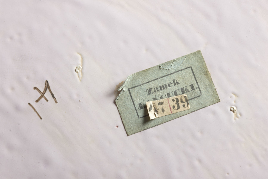 duże naczynie cylindryczne, o grubych ściankach, z podstawką. Zewnętrzna powierzchnia ścianek modelowana jest na kształt wiązek łodyg bambusowych przewiązanych wstążką z kokardą. Łodygi malowane są naturalistycznie, w kolorze żółtym i brązowym. Donica i podstawka pokryte są wewnątrz polewą w kolorze liliowym. 