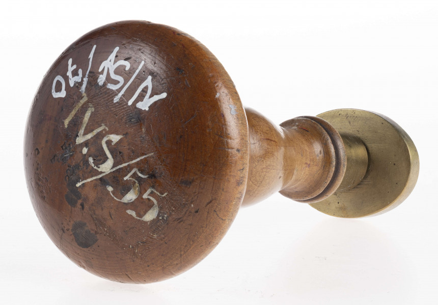 W dolnej części tłoka ukośnie umieszczone obok siebie dwie tarcze z herbami: Jelita i Łada. Herb Jelita zwienczony otwartą koroną i klejnotem; herb Łada ukoronowanym małym hełmem i klejnotem. Nad tarczami Oko Opatrzności w promienistej glorii. Obramowanie gładkim otokiem.
