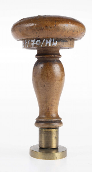 W dolnej części tłoka ukośnie umieszczone obok siebie dwie tarcze z herbami: Jelita i Łada. Herb Jelita zwienczony otwartą koroną i klejnotem; herb Łada ukoronowanym małym hełmem i klejnotem. Nad tarczami Oko Opatrzności w promienistej glorii. Obramowanie gładkim otokiem.
