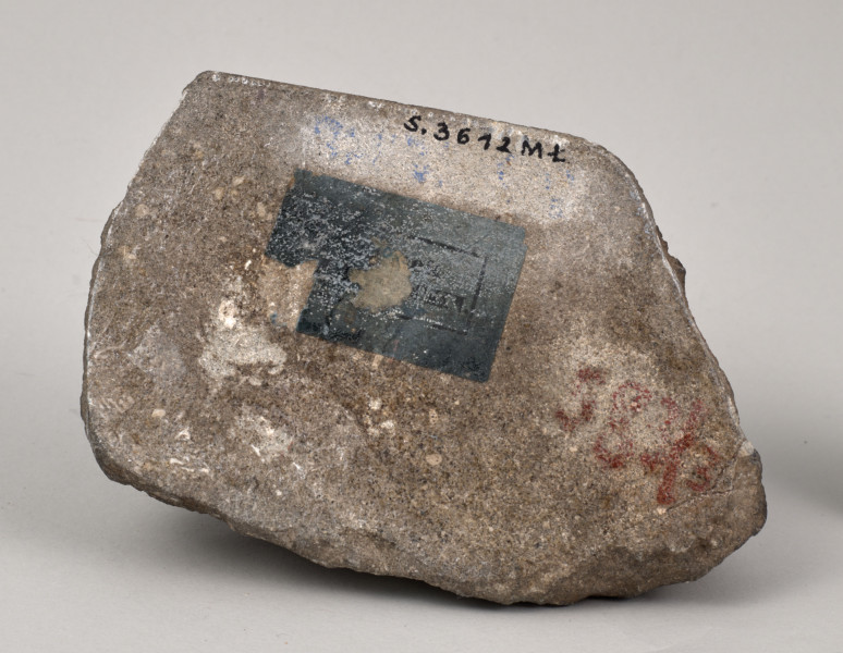 Przycisk do papieru w kształcie leżącego kamiennego nieforemnego prostopadłościanu o nieregularnych krawędziach na górze ma zamontowanym okrągłym mosiężnym uchwyt, z tego samego materiału wykonana jest podłużna ozdobna tabliczka ozdobiona motywem muszli mocowana do kamienia bez widocznych ćwieków z napisem „Stare Sioło 1872