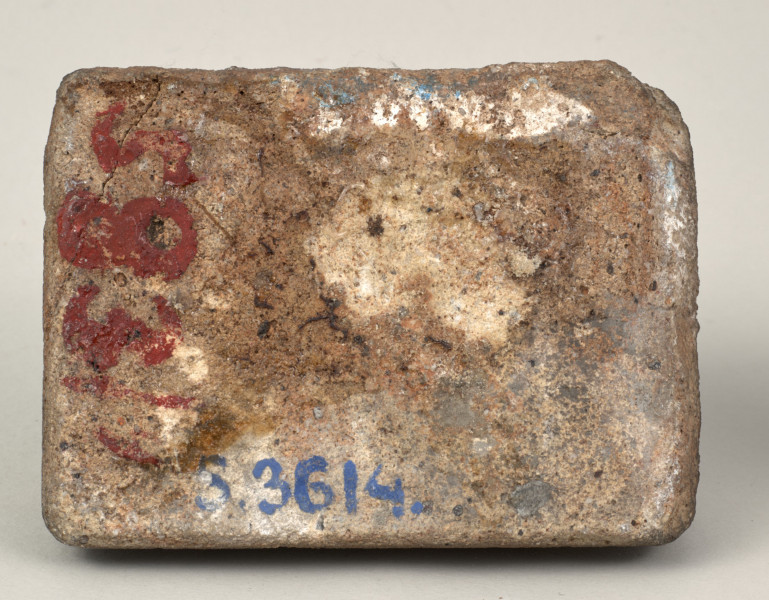 Przycisk do papieru w kształcie leżącego kamiennego prostopadłościanu o lekko zaokrąglonych krawędziach, na górze ma zamontowany okrągły mosiężny uchwyt na stylizowanym kartuszu, z  tego samego materiału wykonana jest podłużna tabliczka mocowana do kamienia dwoma ćwiekami z napisem „Kijów – Złota Brama 1871