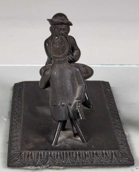 Forma przestrzenna ukazuje dwóch mężczyzn siedzących przy stoliku i grających w karty. Podstawa prostokątna ozdobiona wokół pasem ornamentalnym w motyw roślinny