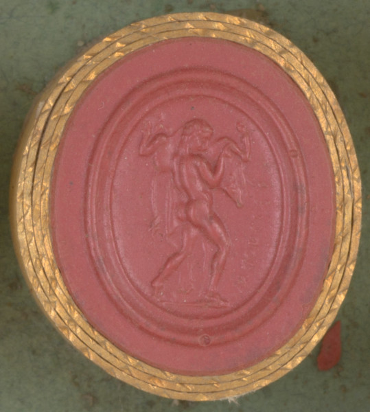 czerwona owalna gemma w grubym złotym obramowaniu, stojący nagi mężczyzna dźwigający zabitego byka na lewym ramieniu, mężczyzna ma lwią skórę przerzuconą przez ramię, scena widoczna z boku.