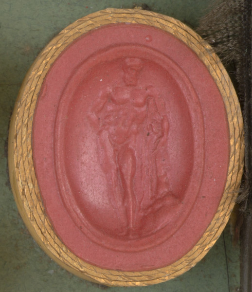 czerwona owalna gemma w grubym złotym obramowaniu, nagi, umięśniony mężczyzna stojący przodem, oparty o maczugę, na której wisi skóra lwa.