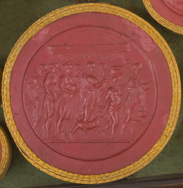 czerwona owalna gemma w grubym złotym obramowaniu; scena wielofiguralna, 8 osób uczestniczy w procesji: 5 kobiet w strojach antycznych, 2 mężczyzn i satyr. Na początku pochodu idzie kobieta ubrana w długi peplos, trzymająca w jednej ręce gałązkę, a w drugiej misę z darami, za nia idzie niski brodaty mężczyzna z nagim torsem, przewiązany chustą w pasie; mężczyzna niesie na głowie misę, a prawą ręką ciągnie za rogi dorosłego kozła; za tym mężczyzną idą dwa kolejni ubrani w chitony, jeden starszy z brodą, drugi młodszy; za nimi idą cztery kobiety.W tle widoczny budynek (świątynia?) przybrany kwiatową girlandą. Przed procesją na postumencie przystrojonym girlandą stoi czara z płonącym ogniem