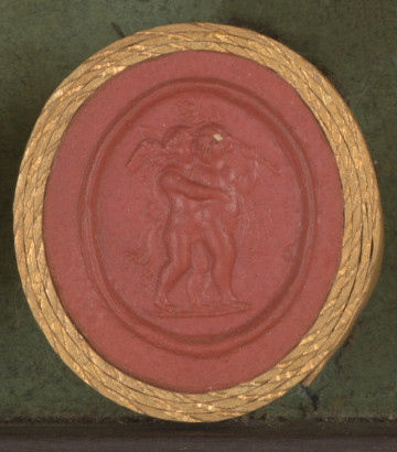 czerwona owalna gemma w grubym złotym obramowaniu; dwa nagie i putta obejmujące się; putto po lewej to uskrzydlowy chłopiec obejmujący dziewczynkę, dziewczynka stoi do niego tyłem, jednak głowy mają zwrócone w swoją stronę, dziewczynka trzyma podniesioną w górę laskę zakończoną szyszką (tyrs); w tle widoczny udrapowany materiał oraz łuk i kołczan ze strzałami