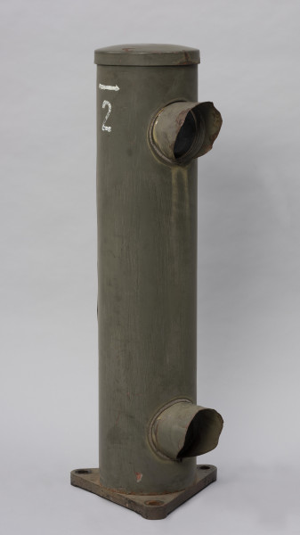 Systemowe Urządzenie Sygnalizacyjne - Ujęcie ze skosu z lewej strony; Urządzenie sygnalizacyjne będące fragmentem systemu ochrony granic PRL. Składa się z dwóch metalowych słupów, w których zamontowano czujniki na podczerwień. Każde z urządzeń znajduje się w obudowie o kształcie walca zamontowanej na trójkątnej podstawie. Zaopatrzone jest w dwie soczewki umieszczone jedna nad drugą.