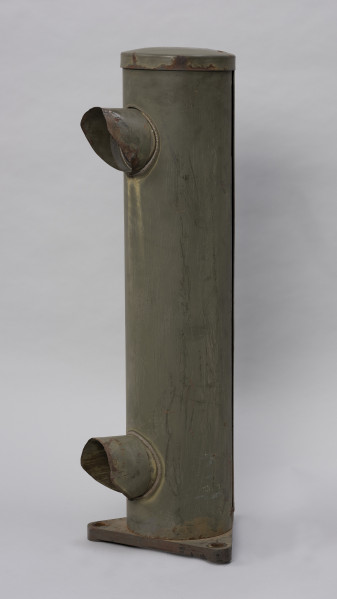 Systemowe Urządzenie Sygnalizacyjne - Ujęcie ze skosu z prawej strony; Urządzenie sygnalizacyjne będące fragmentem systemu ochrony granic PRL. Składa się z dwóch metalowych słupów, w których zamontowano czujniki na podczerwień. Każde z urządzeń znajduje się w obudowie o kształcie walca zamontowanej na trójkątnej podstawie. Zaopatrzone jest w dwie soczewki umieszczone jedna nad drugą.