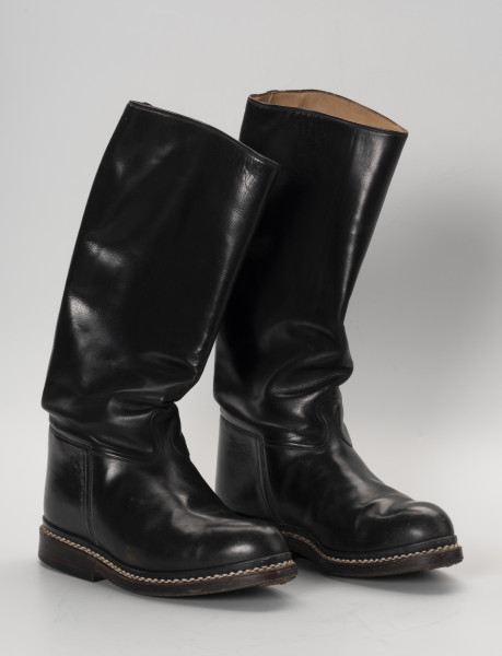 para butów oficerek - Ujęcie z lewej; Para męskich, skórzanych butów z wysokimi cholewami, zrobionych na wzór oficerek przedwojennych. Przyszwy i cholewy wykonane z barwionej na czarno skóry, przyszyte dratwą do podeszwy podwójnymi szwami.