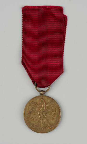 Medal Pamiątkowy Za Wojnę 1918-1921 - awers; Okrągły medal z oczkiem do zawieszania na górze. Na awersie: godło państwowe – orzeł w koronie według wzoru z 1927 roku, na piersi którego znajduje się Krzyż Wojenny Orderu Virtuti Militari. Po obu stronach godła, nad szponami znajdują się rozpisane na okręgu daty 1918 i 1921.
