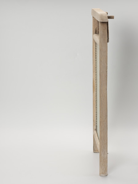 Tara do prania - lewy bok; Tara do prania złożona z prostokątnej, szklanej tafli osadzonej w drewnianej ramie. Szklana część jednostronnie karbowana. Oprawa z dwóch pionowych listew tworzących w dolnej części nóżki, dwóch poprzecznych listew stanowiących oparcie dla tafli oraz górnej profilowanej z wystającymi końcówkami stanowiącymi uchwyt. Od tyłu z prawej strony pomiędzy listwą uchwytową, a górną poprzeczką przybita prostokątna, cienka deska. Powyżej w listwie uchwytowej z prawej wkręcone dwa drewniane kołki umożliwiające zawieszenie tary na brzegach balii.