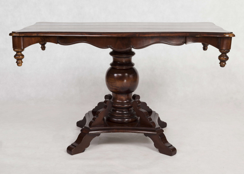 Stół na jednej nodze, blat prostokątny o brzegu falistym obwiedzionym profilowaną listwą. Oskrzynienie wykrojone faliście z brzegiem obwiedzionym odcinkami półwałka zakończonymi wolutowo, w narożnikach dodane toczone sterczynki. Noga tralkowa, profilowana,  na czworobocznym cokole z czterema ozdobnie wycinanymi nóżkami.  