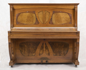 S/Mb/172/ML Pianino w obudowie z jasnego drewna, częściowo fornirowane czeczotą, zdobione roślinną dekoracją snycerską. Klawisze wyłożone kością słoniową oraz drewnem hebanowym.