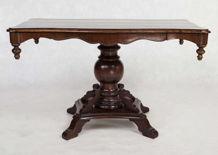 Stół na jednej nodze, blat prostokątny o brzegu falistym obwiedzionym profilowaną listwą. Oskrzynienie wykrojone faliście z brzegiem obwiedzionym odcinkami półwałka zakończonymi wolutowo, w narożnikach dodane toczone sterczynki. Noga tralkowa, profilowana,  na czworobocznym cokole z czterema ozdobnie wycinanymi nóżkami.  