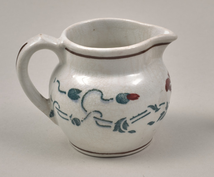 Dzbanuszek - mały, fajansowy z pękatym brzuścem i krótką szyjką o szerokiej gardzieli, którą w jednym miejscu wydłuża trójkątny wylew