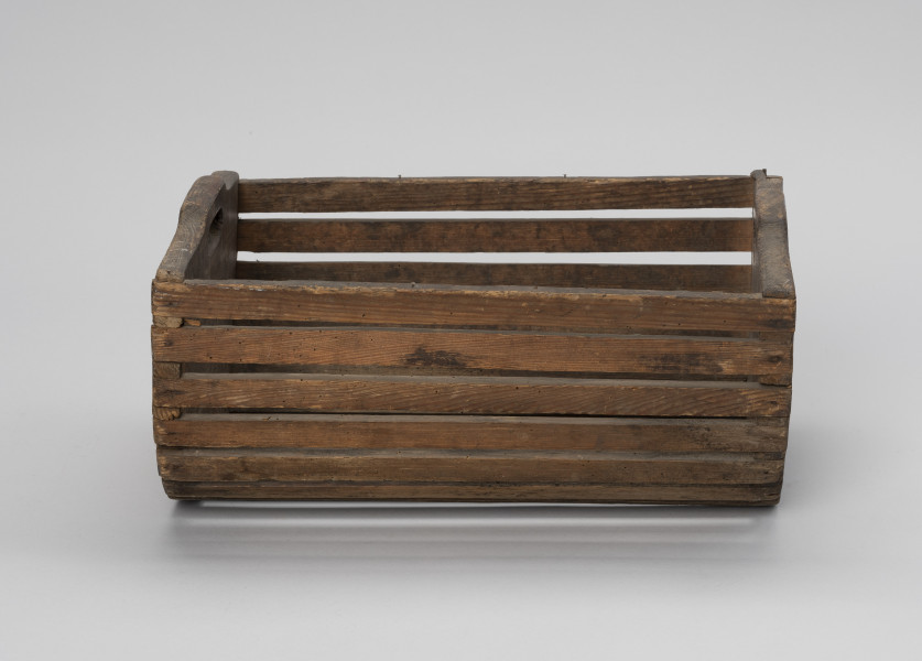 Skrzynka do przechowania i przenoszenia przynęty - Ujęcie z tyłu; Drewniana skrzynka w formie niecki, w przekroju poprzecznym – półkolista. Dłuższe boki i podstawę wykonana z płaskich klepek przytwierdzonych do krótszych, pełnych boków zaopatrzonych w uchwyty, Klepki do boków przybite gwoździkami.