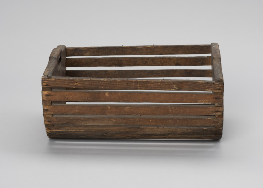 Skrzynka do przechowania i przenoszenia przynęty - Ujęcie z przodu; Drewniana skrzynka w formie niecki, w przekroju poprzecznym – półkolista. Dłuższe boki i podstawę wykonana z płaskich klepek przytwierdzonych do krótszych, pełnych boków zaopatrzonych w uchwyty, Klepki do boków przybite gwoździkami.