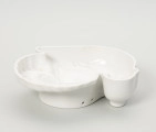 forma ceramiczna - Ujęcie z tyłu; Fajansowe, szkliwione jednolicie na biało naczynie w kształcie indyka. Realistyczna postać ptaka odwzorowana w postaci wgłębnego wzoru. Dno z wyraźnie wyodrębnioną stopką w części środkowej. Na stopce dwa otwory dające możliwość powieszenia naczynia na ścianie lub w kredensie.