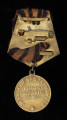 medal Za zwycięstwo nad Niemcami w Wielkiej Wojnie Narodowej 1941-1945 - Ujęcie z tyłu; Medal jest okrągły, z czarno-pomarańczową wstążką na stelażu, z baretką wykonaną z tego samego materiału. Na rewersie widnieją napisy w języku rosyjskim – w otoku: ЗА ПОБЕДУ НАД ГЕРМАНИЕЙ oraz centralnie: В ВЕЛИКОЙ ОТЕЧЕСТВЕННОЙ ВОЙНЕ 1941—1945 ГГ. Poniżej napisu znajduje się pięcioramienna gwiazda.