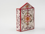retablo - Ujęcie z przodu z lewej; Jasna, bogato dekorowana kolorowymi wzorami florystycznymi, prostopadłościenna, skrzynka (kapliczka) z dwuskrzydłowymi drzwiczkami, zwieńczona trójkątną koroną.