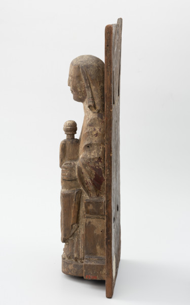 Tronująca Madonna z Dzieciątkiem - Ujęcie z prawej; Niewielka figura tronującej Marii z dzieciątkiem o zwartej bryle, przytwierdzona do wysokiego zaplecka o geometrycznym zwieńczeniu, polichromowana. Powierzchniowe ubytki drewna i otwory po drewnojadach. Polichromia zachowana szczątkowo.