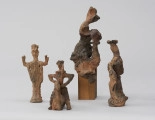 zespół rzeźb; Zmierzch królów - ujęcie z przodu; Zespół surrealistycznych antropomorficznych i zoomorficznych figur o ceglasto-szarej barwie, od lewej:
a) Postać męska o zwartych nogach, uniesionych w górę, zgiętych w łokciach ramionach. Sterczące nakrycie głowy, spodnie bufiaste na biodrach, na nogach poprzecznie nałożone paski gliny. Na torsie i szyi ryty.
b) Jeździec na koniu bez nóg. Szeroko rozstawione ręce, wsparte dłońmi o biodra, w lewej sterczący w górę miecz. Głowa mała na długiej szyi, na szyi kryza. Na torsie rytem zaznaczone łuski pancerza. W stosunku do postaci koń mały, schematycznie potraktowany.
c) Ogólnie potraktowanej stojącej na postumencie postaci kobiecej. Głowa odchylona w prawo, w tył, tors w lewo, fragmentarycznie zaznaczony. Od bioder draperie fałd spódnicy. Po prawej, przy postaci pionowa forma połączona trzema poziomymi trzpieniami z postacią. Na wysokości torsu postaci forma nieco powiększa się i łączy z postacią.
d) Skręcona spiralnie, wysmukła postać kobieca o tektonicznej formie. Twarz pociągła, na głowie duży, płaski beret. Na grubej szyi rytmiczne krążki. Prawe ramię opuszczone ukośnie w dół, w ręce wachlarz. Na ramieniu trzy czarne krążki. Na podstawie 4 