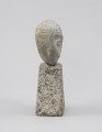 rzeźba; głowa - Ujęcie z prawej; Spłaszczona, bliska owoidalnej głowa, osadzona na kostce w kształcie ściętego ostrosłupa. Rysy twarzy: konturowo zaznaczone oczy. Ryt ornamentalny włosów widoczny tylko na froncie skały, bezpośrednio wokół twarzy.