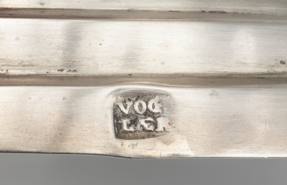 cukiernica do cukru pudru - detal; na cokoliku stopy w prostokątnym polu o zaokrąglonych narożnikach napis  VOG | LAER