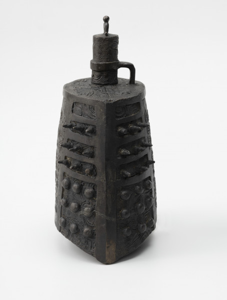 zhong (dzwon chiński) - ujęcie z prawej; Wykonany z brązu dzwon o soczewkowatym przekroju poprzecznym. Na płaskim hełmie znajduje się korona w formie trzpienia, na szczycie zwieńczonym kuleczką i drugim, wygiętym pod kątem prostym, wychodzącym z hełmu i połączonym z trzpieniem za pomocą okrągłej obejmy. Na bogaty ornament reliefowy w postaci siatki wzoru geometrycznego (meander) i zoomorficznego (przedstawienia wężowatych stworzeń, być może smoków) po bokach nałożono kolce mei (w górnej części) oraz guzki (w dolnej części). Dzwon tego typu nie posiada serca, jego środek pozostaje pusty.