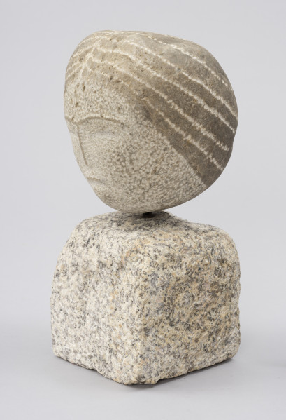 rzeźba; Prasłowianka I - ujęcie przodu ze skosu z prawej; Owalna bryła naturalnego kamienia polnego osadzona na kostce kamiennej. Skała tworząca głowę przekształcona w niewielkim stopniu. Rysy twarzy płytko cięte i przedstawione schematycznie. Wyraźna linia grzbietu nosa, rozwidlająca się na szczycie w łuki brwiowe powstała przez zachowanie cienkich pasów naturalnej warstwy zewnętrznej kamienia o ciemniejszym zabarwieniu. Podobnie wydobyto cechy fryzury - punktowym rytowaniem zaznaczony został przedziałek po środku głowy oraz linie wyznaczające szerokie pasma prostych, ciemnych włosów, biegnące od przedziałka do tyłu głowy, sugerując związanie w koński ogon.