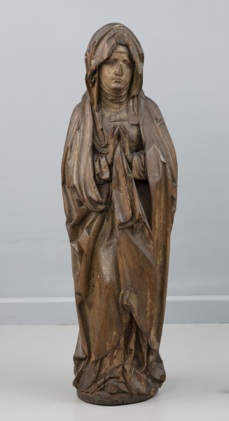 Matka Boska Bolesna z Chociwla - Ujęcie z przodu; Kobieca figura pełnoplastyczna, polichromowana. Przedstawia Marię stojącą frontalnie z dłońmi uniesionymi w geście modlitewnym. Ubrana jest w suknię o długich rękawach i szeroki modelowany światłocieniowo płaszcz otulający sylwetkę, którego krawędź podłożoną pod prawym przedramieniem Marii opada z przodu szeroką trójkątnie zakończoną fałdą. Na głowie chusta osuwająca się na skronie zebrana jednym końcem pomiędzy dłonie. Pod spodem widoczna jest drobno marszczona podwika szczelnie okrywająca dekolt i szyję. Owalna twarz o smutnym wyrazie z ustami i oczami o opadających kącikach. Figura wewnątrz wydrążona. Z tyłu wzdłuż pleców i partii nóg długi prostokątny ruchomy element zakrywający otwór po wydrążeniu rzeźby, o powierzchni dopasowanej do fałdowań płaszcza. Widoczne są drobne ubytki drewna w górnej partii chusty, na końcówkach palców dłoni i przy podstawie. Polichromia zachowana częściowo.