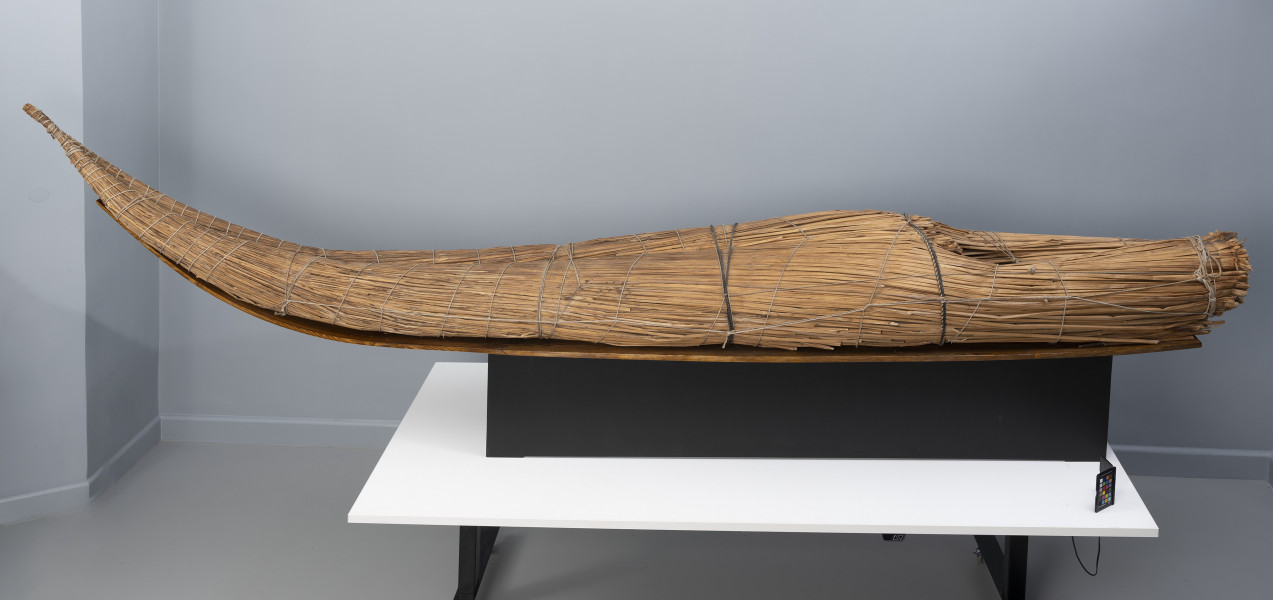 caballito de totora (łódź trzcinowa) - Ujęcie z przodu; Ponad czterometrowa łódź trzcinowa o naturalnym jasnobrązowym kolorze z wysoko zadartym ku górze długim, zwężającym się dziobem z lewej oraz grubą, płasko ściętą rufą z prawej. Kształtem przypomina gruby cios słonia. Została zbudowana z dwóch wiązek trzciny mocno skrępowanych przez poprzeczne wiązania. W ten sposób nadano łodzi pożądany, żeglowny kształt. Wśród wiązek trzcinowych tworzących rufę uformowano trójkątne zagłębienie służące do przechowywania narzędzi rybackich (sieci, lin, pułapek) i złowionych zdobyczy.
