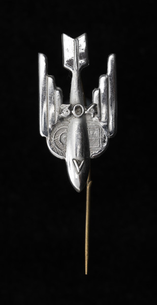 odznaka okolicznościowa - Ujęcie z przodu; Odznaka ma kształt uskrzydlonej, lecącej w dół bomby, z literą V umieszczoną na skorupie. W centrum, między skrzydłami znajduje się numer dywizjonu: 304. Po bokach korpusu bomby umieszczone są symbole lotnictwa: polskiego, w formie połowy szachownicy – po prawej oraz brytyjskiego (RAF-u), połowa tarczy strzeleckiej z koncentrycznymi okręgami – po lewej. Odznaka mocowana na szpilkę.