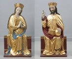 dwufigurowa grupa płaskorzeźb ołtarzowych - Ujęcie z przodu; Dwie płaskorzeźbione figury przedstawiają grupę Koronacji Marii. Na szerokich ławach tronują obok siebie Maria (po lewej stronie) i Chrystus. Postaci ubrane są w długie tuniki przewiązane w pasie i płaszcze spięte klamrą powyżej piersi. Miękkie, lejące się ku podstawie rzeźb złociste tkaniny szat połyskują efektownie marszczeniami o łagodnych grzbietach. Na głowach wysokie złocone korony o gładkiej obręczy, zwieńczone zygzakiem. Maria lekko przechyla głowę w kierunku Chrystusa, dłonie trzymając w geście modlitewnym przy piersi. Jej młodzieńczą twarz o wysokim czole i łagodnych rysach otaczają pasma długich falujących, złocistych włosów. Chrystus swoją prawą rękę podnosi w geście błogosławieństwa, lewą opiera na złotej kuli trzymanej na kolanie. Jego pociągłą twarz o wyraźnie zaznaczonych kościach policzkowych pokrywa ciemny zarost. Długie włosy opadają na ramiona. Tyły rzeźb opracowany płasko. Widoczne pęknięcie drewna na twarzy Chrystusa wzdłuż jego prawej skroni, poprzez policzek w kierunku ust. Fleurony wieńczące obręcze koron nie zachowały się. Złocenia płaskorzeźb częściowo rekonstruowane.