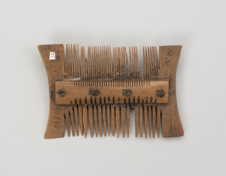 grzebień dwustronny grupa IIB, typ III - Ujęcie z tyłu; Niewielki, dwustronny grzebień, wykonany z czterech płytek wyciętych z poroża, ułożonych obok siebie i przymocowanych do obustronnie występujących okładzin nitami wykonanymi ze stopu miedzi. Każdy nit znajduje się pośrodku jednej płytki. Po zmontowaniu konstrukcji wycinano za pomocą precyzyjnych piłek zęby, gęstsze po jednej, z rzadziej rozmieszczona po drugiej stronie grzebienia. Powierzchnia została wygładzona, usunięto ślady obróbki surowca.