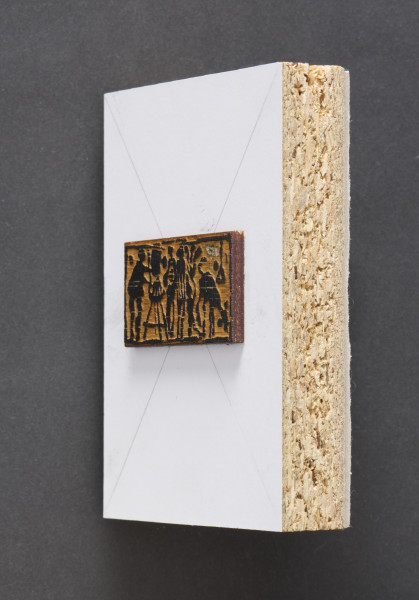 klocek drzeworytniczy - Klocek drewniany, z wyrytym tłem tworzącym wypukłą powierzchnie odbicia matrycy przedstawiającą malarza przy sztaludze po prawej stronie, dwie postacie oraz zwierzę po stronie lewej klocka drzeworytniczego. Matryca przymocowana do prostokątnego kawałka płyty wiórowej z naklejonym od przodu białym laminatem oraz szarą tekturą od tyłu.