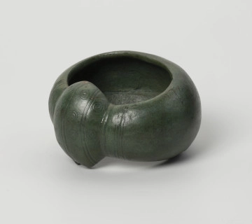 MNS/A/17859 kopia bransolety nerkowatej z Kolkowa - Ujęcie przodu ze skosu z prawej; Bransoleta o szerokiej obręczy (5,9 cm), silnie wypukła. Jej brzegi są mocno zagięte do środka, co daje C-kształtny przekrój poprzeczny. Oba końce obręczy łączy duże zgrubienie, tzw. nerka. Końce i zgrubienie nerkowate zostały ozdobione pasmami zwielokrotnionych linii (3 pasma przypadają na zgrubienie, a 4 pasma na końce obręczy), które biegną poprzecznie w stosunku do obręczy. Pomiędzy pasmami na zgrubieniu nerkowatym znajduje się tzw. ornament oczkowy (współśrodkowe podwójne okręgi z centralnie usytuowaną kropką-wgłębieniem). Bransoleta ma zielony kolor. Brzeg nerki ma w jednym miejscu zamarkowane uszkodzenie, wzorowane na oryginale bransolety.