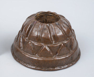 ujęcie 3/4. Kopulaste naczynie miedziane w kształcie turbana. Pośrodku otwór kominka. 