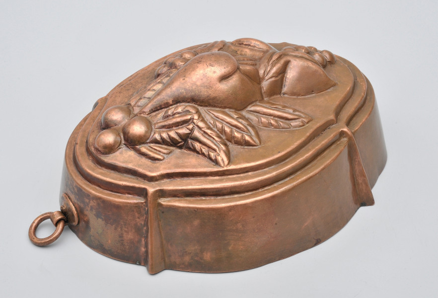 ujęcie 3/4. Naczynie o wysokim brzegu, nad którym dwa uskoki i wypukła dekoracja na płasko ściętej powierzchni.