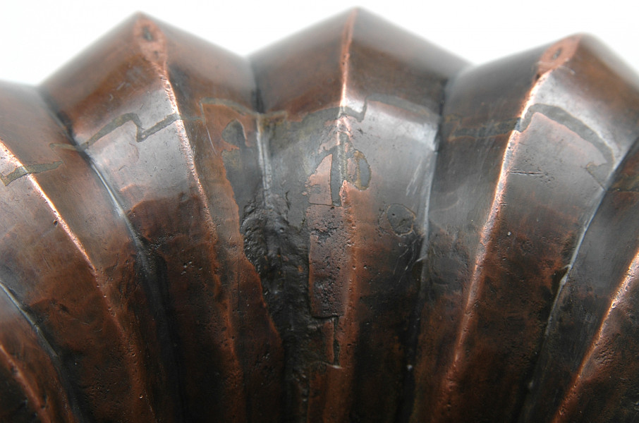 zbliżenie na segmenty ośmioczęściowej rozety z wypiętrzonymi krawędziami. Kolorystyka rdzawo-szara.